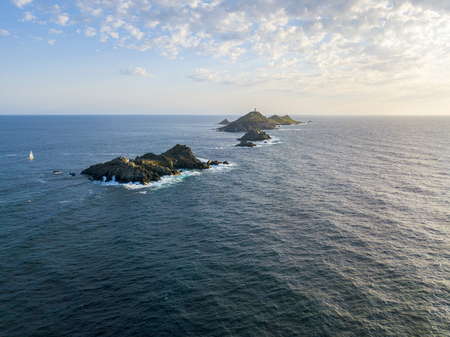 Aerial view of the Bloods Islands and Lighthouse, Corsica, France: Rocks, waves and sailboat. Four islands of dark red porphyry, small archipelago in the Gulf of Ajaccio. Sunsetの写真素材