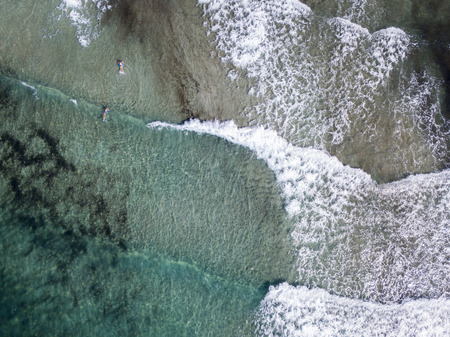 Aerial view of the rocks on the sea. Overview of seabed seen from above, transparent water. Swimmers, bathers floating on the waterの写真素材