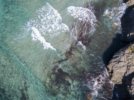 Aerial view of the rocks on the sea. Overview of seabed seen from above, transparent water. Swimmers, bathers floating on the water.の写真素材