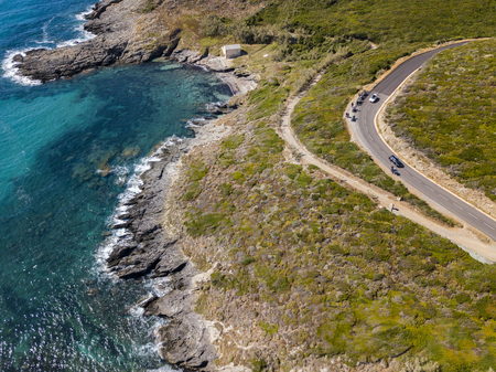 Aerial view of Corsica, winding roads and coves with crystalline sea. Motorcyclists parked on the edge of a road. Cap Corse Peninsula, Corsica. Coastline. Anse d'Aliso. Gulf of Aliso. franceの写真素材