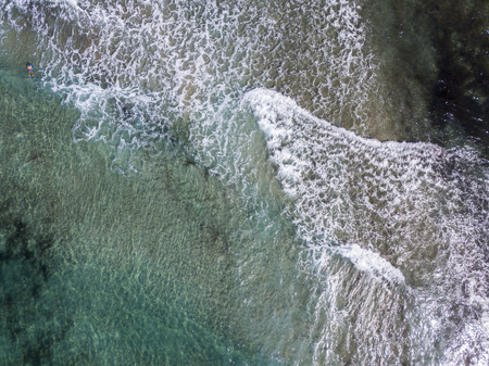 Aerial view of the rocks on the sea. Overview of seabed seen from above, transparent water. Swimmers, bathers floating on the waterの写真素材