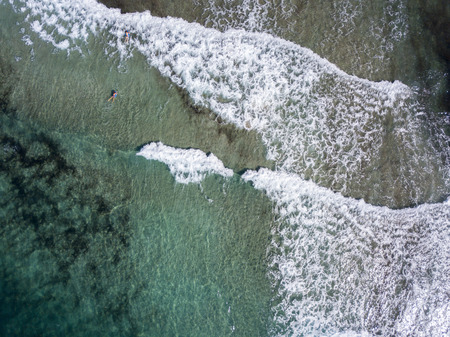 Aerial view of the rocks on the sea. Overview of seabed seen from above, transparent water. Swimmers, bathers floating on the waterの写真素材