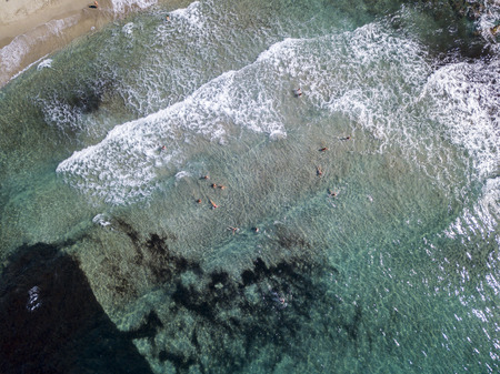 Aerial view of the rocks on the sea. Overview of seabed seen from above, transparent water. Swimmers, bathers floating on the waterの写真素材