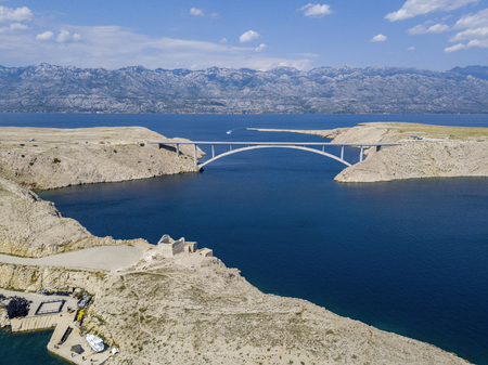 Aerial view of the bridge of the island of Pag, Croatia. Ruins of ancient fortress Fortica on Pag Island, Croatia. Cars crossing the bridge seen from aboveの写真素材