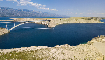 Aerial view of the bridge of the island of Pag, Croatia. Speedboat passing under the bridge at high speed. Ruins of ancient fortress Fortica on the island of Pag, Croatiaの写真素材
