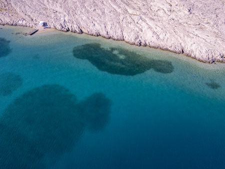 Aerial view of a trendy tent, cover from the sun. Rocks on the sea and transparent sea floor. Tent...