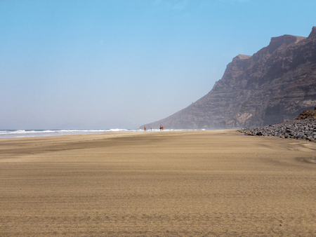 People walking on the Famara seafront, beach and mountains overlooking the ocean. Lanzarote, Canary Islands, Spain. Africaの写真素材