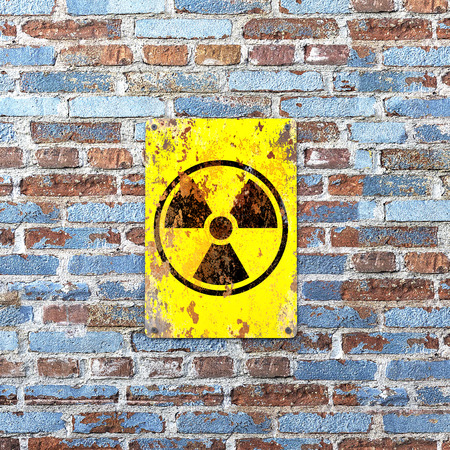 Nuclear site, sign hanging on a brick wall. Indication of the presence of a radioactive area, 3d render. Nuclear weapons. Dangerous site.の写真素材