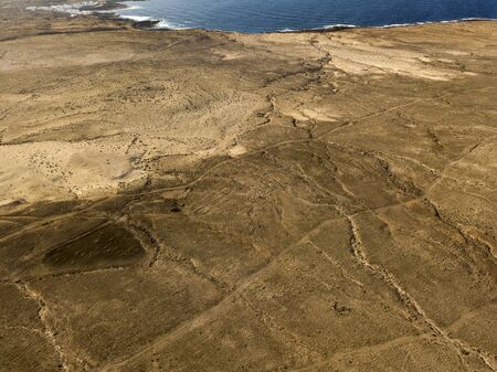 Aerial view of a desert landscape on the island of Lanzarote, Canary Islands, Spain. Desert background, texture. Sand and desolate land. Ocean in the backgroundの写真素材