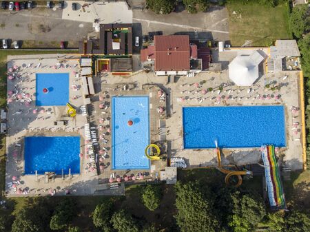 Aerial view of swimming pools. Summer and holiday periods, crystal clear water. Trampolines, slides and water games. Complex of pools, umbrellas and deck chairs. Green area. Il Gabbiano in Limbiate, Milan, Italyの写真素材
