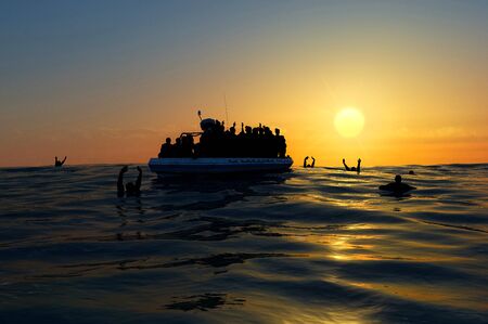 Refugees on a rubber boat in the middle of the sea that require help. Sea with people asking for help. Migrants crossing the seaの写真素材