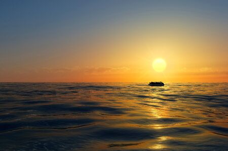 Refugees on a rubber boat in the middle of the sea that require help. Sea with people asking for help. Migrants crossing the seaの写真素材