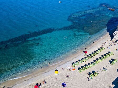 Aerial view of a beach with umbrellas and bathers. Promontory of the Sanctuary of Santa Maria dell'Isola, Tropea, Calabria, Italy.の写真素材