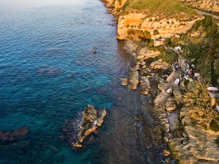 Aerial view of fishermen on the rocks, shacks and fishing posts on a cliff by the sea. Disused houses, huts, shelters and slums. Italian coast, Pizzo Calabro, Calabria. italyの写真素材