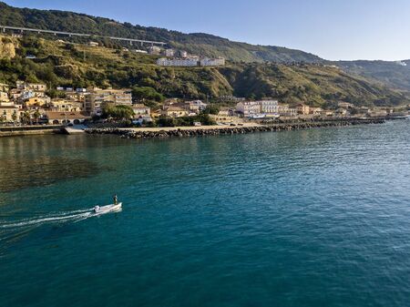 Aerial view of a boat seen from above, powered by an engine. Blue sea that surrounds a boat that crosses it. People inside a boat. 22/10/2019. Pizzo Calabro, Calabria, Italyの写真素材