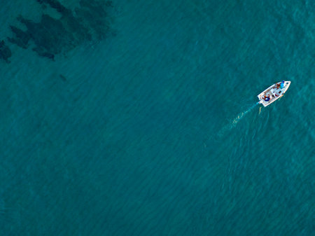 Aerial view of a boat seen from above, powered by an engine. Blue sea that surrounds a boat that crosses it. People inside a boat. 22/10/2019. Pizzo Calabro, Calabria, Italyのeditorial素材