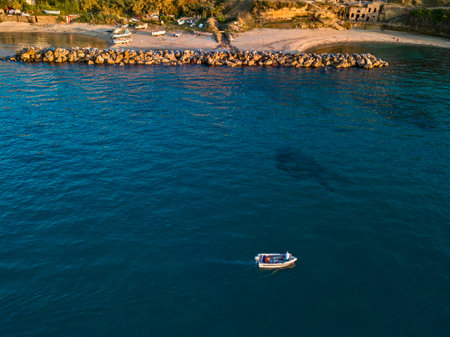 Aerial view of a boat seen from above, powered by an engine. Blue sea that surrounds a boat that crosses it. People inside a boat. Church of Piedigrotta. 22/10/2019. Pizzo Calabro, Calabria, Italyのeditorial素材