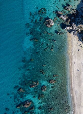 Aerial view of Tropea beach, crystal clear water and rocks that appear on the beach. Calabria, Italy. Swimmers, bathers floating on the water. Tyrrhenian Sea. Coastline of Calabriaの写真素材