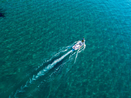 Aerial view of a boat seen from above, powered by an engine. Blue sea that surrounds a boat that crosses it. People inside a boat. 22/10/2019. Pizzo Calabro, Calabria, Italyのeditorial素材