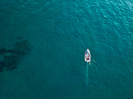 Aerial view of a boat seen from above, powered by an engine. Blue sea that surrounds a boat that crosses it. People inside a boat. 22/10/2019. Pizzo Calabro, Calabria, Italyのeditorial素材