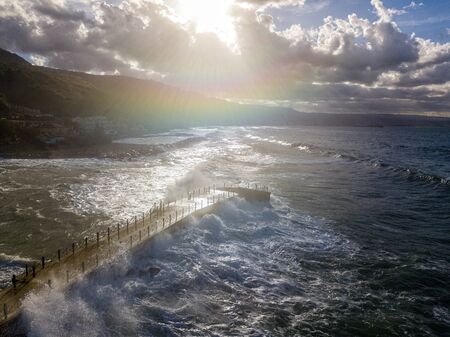 Aerial view of a pier with rocks and rocks on the sea. Pizzo Calabro pier, panoramic view from above. Broken pier, force of the sea. Power of Waves. Natural disasters, climate change. Calabria, Italyの写真素材