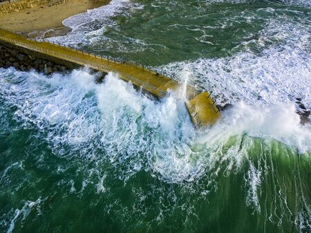 Aerial view of a pier with rocks and rocks on the sea. Pizzo Calabro pier, panoramic view from above. Broken pier, force of the sea. Power of Waves. Natural disasters, climate change. Calabria, Italy.の写真素材