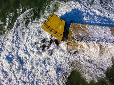 Aerial view of a pier with rocks and rocks on the sea. Pizzo Calabro pier, panoramic view from above. Broken pier, force of the sea. Power of Waves. Natural disasters, climate change. Calabria, Italy.の写真素材