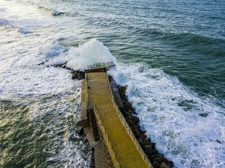 Aerial view of a pier with rocks and rocks on the sea. Pizzo Calabro pier, panoramic view from above. Broken pier, force of the sea. Power of Waves. Natural disasters, climate change. Calabria, Italy.の写真素材