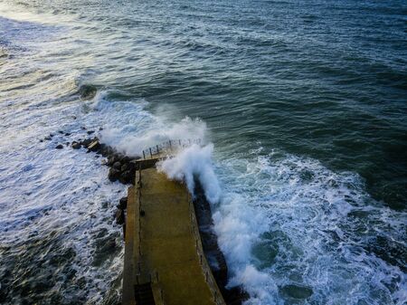 Aerial view of a pier with rocks and rocks on the sea. Pizzo Calabro pier, panoramic view from above. Broken pier, force of the sea. Power of Waves. Natural disasters, climate change. Calabria, Italy.の写真素材