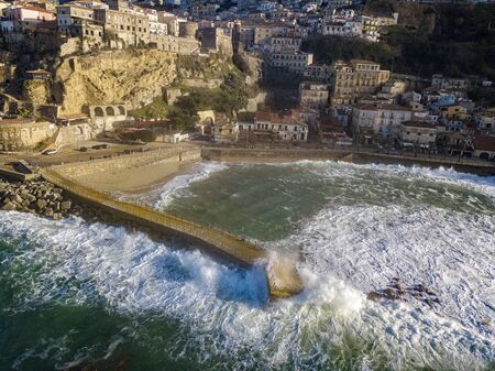 Aerial view of Pizzo Calabro, broken pier, castle, Calabria, tourism Italy. Houses on the rock. On the cliff stands the Murat Aragonese castle. Seafront at sunset. Sea storm and waves with windの写真素材