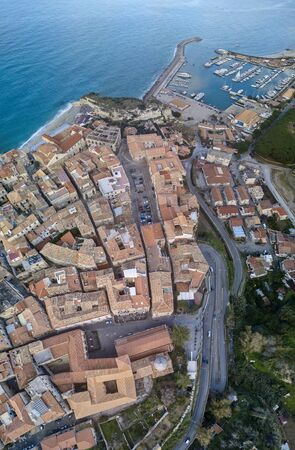 Aerial view of boats moored at the Port of Tropea, Calabria, Italy. Houses overlooking the sea. Beach on the horizon. Italian coastsの写真素材