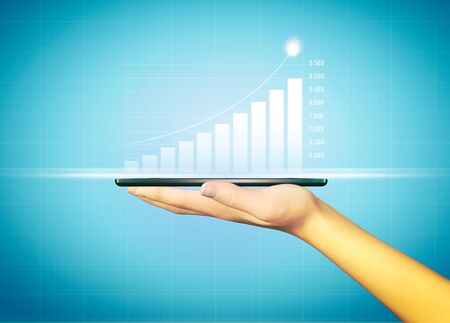 Businesswoman holding a mobile phone and showing holographic graphs and stock market statistics gain profits. Concept of growth planning and business strategy. Good economy, digital screen. HUDの写真素材