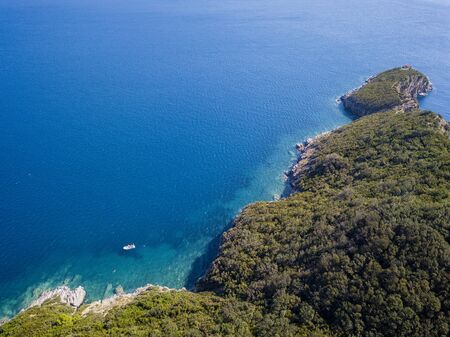 Aerial view of boat, jagged and lush coasts. Mediterranean scrub. Sea, crystal clear water. Sveti Nikola, Budva island, Montenegroの写真素材