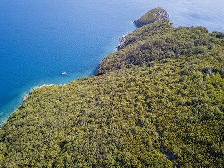 Aerial view of boat, jagged and lush coasts. Mediterranean scrub. Sea, crystal clear water. Sveti Nikola, Budva island, Montenegroの写真素材