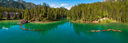 Aerial view of the Lake Braies, Pragser Wildsee is a lake in the Prags Dolomites in South Tyrol, Italy. View of rowboats moored in line. In the background the hotel surrounded by treesの写真素材