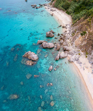 Aerial view of a beach and umbrellas. Tropea, Calabria, Italy. Parghelia. Overview of seabed seen from above, transparent water. Swimmers, bathers floating on the water. Beach and rocks of Vardanelloの写真素材