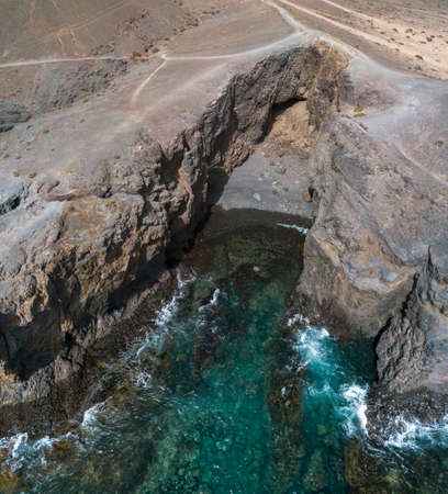 Aerial view of the jagged shores and beaches of Lanzarote, Spain, Canary. Roads and dirt paths. Walking routes to explore the island. Bathers on the beach. Atlantic Ocean. Papagayoの写真素材
