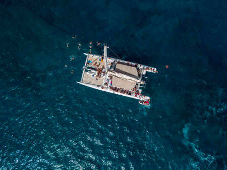 Aerial view of a catamaran with person on board and in the sea, swimming near the coasts of the...