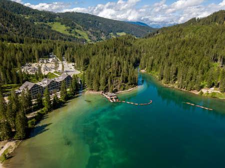 Aerial view of the Lake Braies, Pragser Wildsee is a lake in the Prags Dolomites in South Tyrol, Italy. View of rowboats moored in line. In the background the hotel surrounded by treesの写真素材