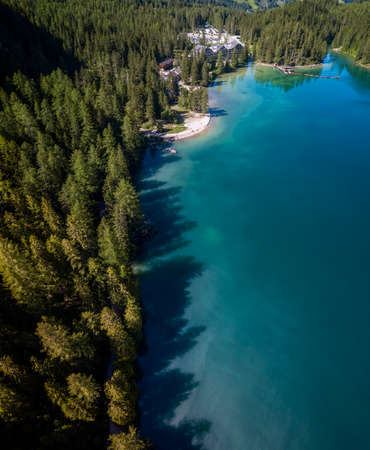 Aerial view of the Lake Braies, Pragser Wildsee is a lake in the Prags Dolomites in South Tyrol, Italy. View of rowboats moored in line. In the background the hotel surrounded by treesの写真素材