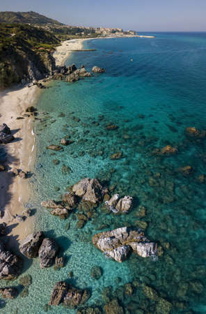 Aerial view of a beach and umbrellas. Tropea, Calabria, Italy. Parghelia. Overview of seabed seen from above, transparent water. Swimmers, bathers floating on the water. Beach and rocks of Vardanelloの写真素材