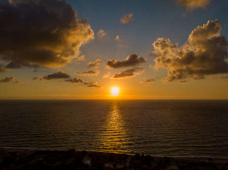 Aerial view of a sunset over the sea in Zambrone, coast of Calabria. Italy. Houses and trees near the beach with umbrellas. Tourist resorts and holidaysの写真素材