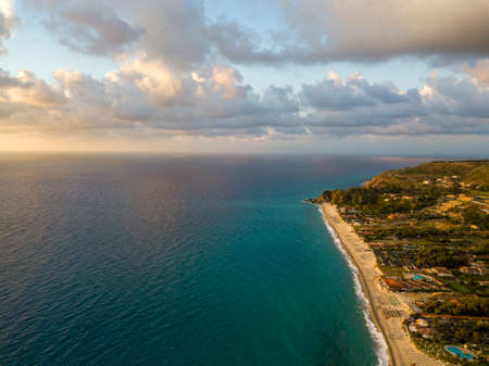 Aerial view of a sunset over the sea in Zambrone, coast of Calabria. Italy. Houses and trees near the beach with umbrellas. Tourist resorts and holidaysの写真素材