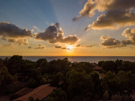 Aerial view of a sunset over the sea in Zambrone, coast of Calabria. Italy. Houses and trees near the beach with umbrellas. Tourist resorts and holidaysの写真素材