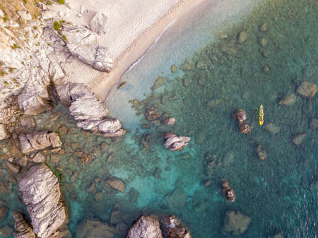 Aerial view of a beach and umbrellas. Tropea, Calabria, Italy. Parghelia. Overview of seabed seen from above, transparent water. Swimmers, bathers floating on the water. Beach and rocks of Vardanelloの写真素材