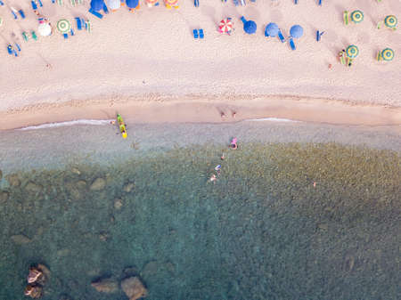 Aerial view of a beach and umbrellas. Tropea, Calabria, Italy. Parghelia. Overview of seabed seen from above, transparent water. Swimmers, bathers floating on the water. Beach and rocks of Vardanelloの写真素材
