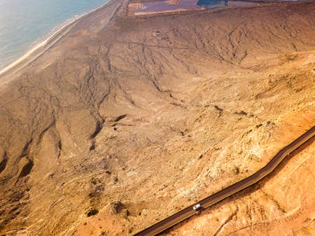 Aerial view from the north tip of the island of Lanzarote, view of the road leading to the Mirador del Rio. Jagged coasts and cliffs overlooking the ocean. A car on the road. Canary Islands, Spainの写真素材