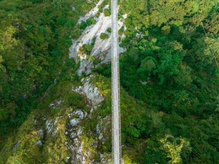 Aerial view of a Tibetan suspended bridge in Nepal is a primitive type of bridge in which the deck lies on two parallel load-bearing cables that are anchored at either endの写真素材