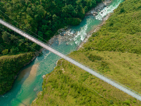 Aerial view of a Tibetan suspended bridge in Nepal is a primitive type of bridge in which the deck lies on two parallel load-bearing cables that are anchored at either end. Wildの写真素材