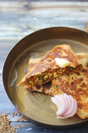 Traditional Indian egg stuffed paratha (bread) served on a traditional plate.の写真素材
